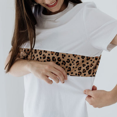 A close up of a hidden zip under a leopard print panel in a white tee for breastfeeding.