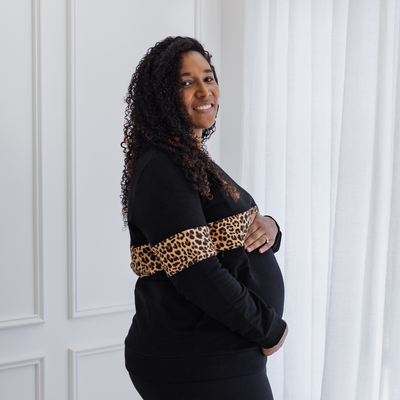 A pregnant woman showing off her bump in a black breastfeeding jumper.