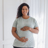 A pregnant mother cradles her bump while wearing a nursing t-shirt.