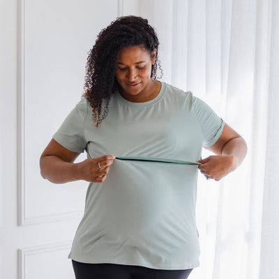 A pregnant woman shows the invisible zip in her green t-shirt.