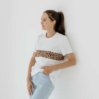 A new mum leans against a wall while mmodelling a fashionable white t-shirt with a hidden nursing zip.