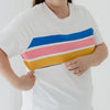 A woman in a white t-shirt with colour stripes, unzipping a hidden zip for breastfeeding access.