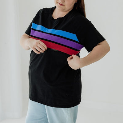 A woman wearing a t-shirt for breastfeeding, shows the hidden zip under the colored panel.