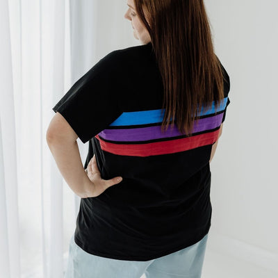 A size XL mum modelling the back of a black breastfeeding top with blue, purple and red stripes across the back and bust.