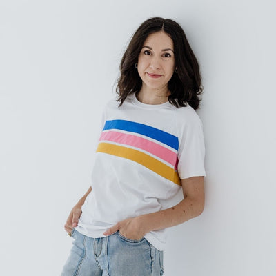 A size S woman modelling a white t-shirt with blue, pink and yellow stripes.