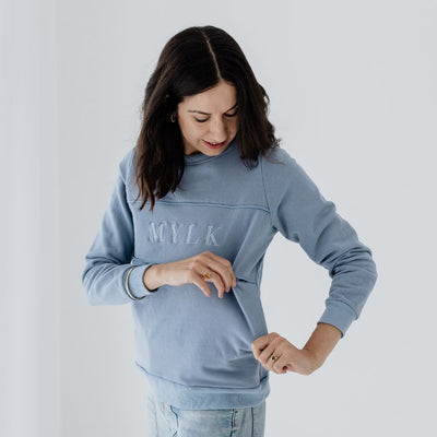 A young mum showing that her blue jumper has a hidden zip to make breastfeeding easy.