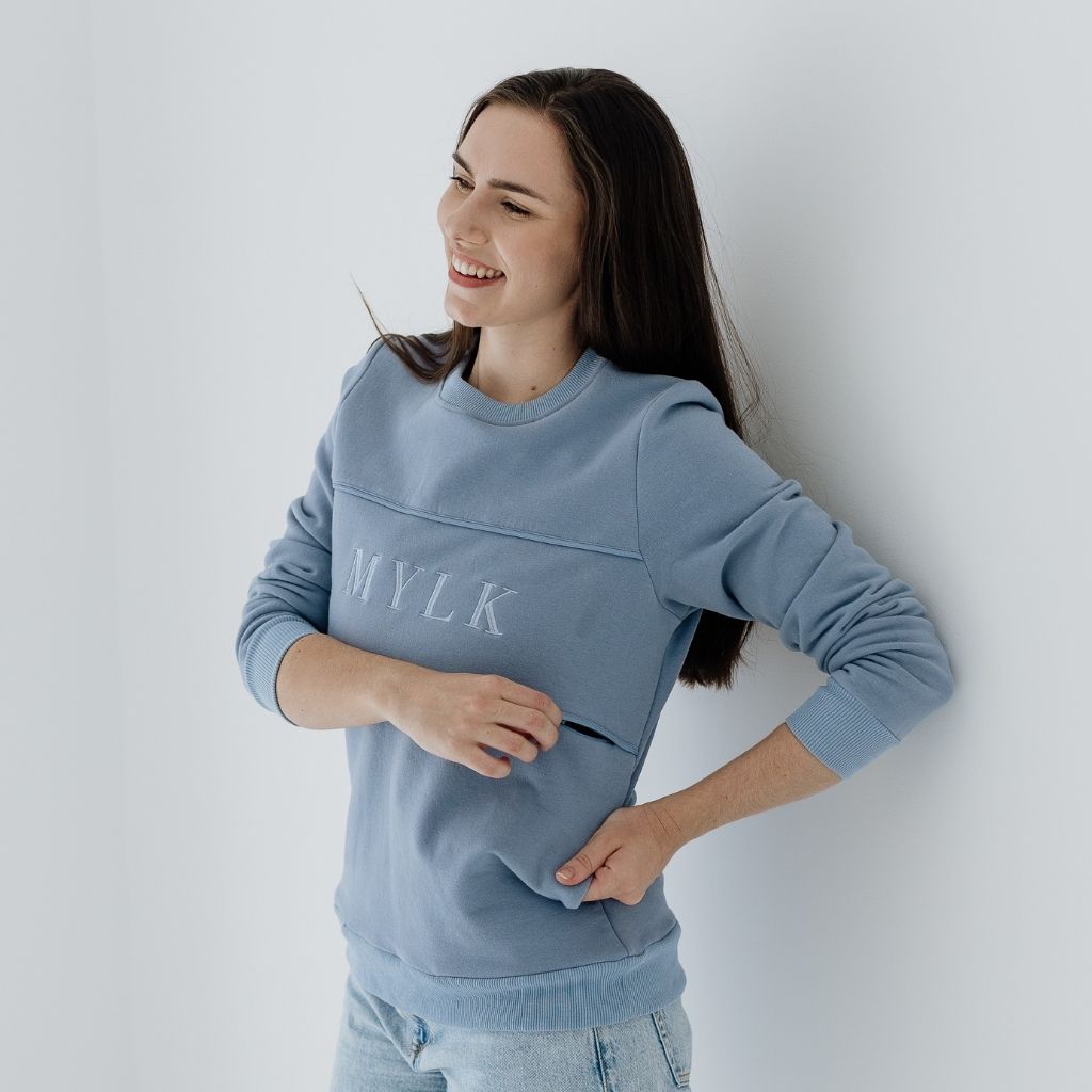 A young mum unzipping a hidden panel in her jumper for breastfeeding.