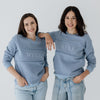Two young mums wearing steel blue jumpers that feature the word MYLK embroidered on the chest.