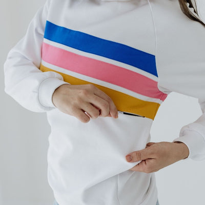 A close up showing an invisible two-way zip under a yellow stripe on a white breastfeeding jumper.