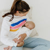A size XS mum breastfeeding her baby while wearing a white nursing jumper with colored stripes.