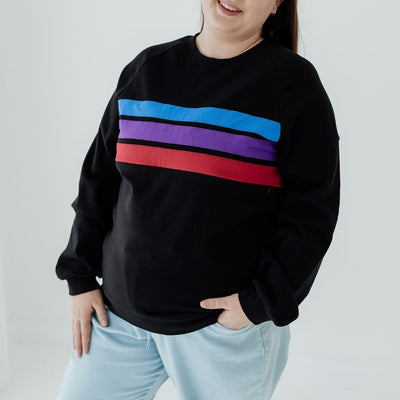A size 16 woman wearing a nursing sweater that has three coloued stripes and pockets.